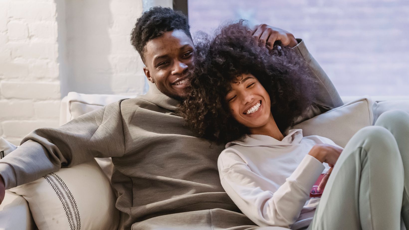black woman smiling at her husband sitting on a sofa